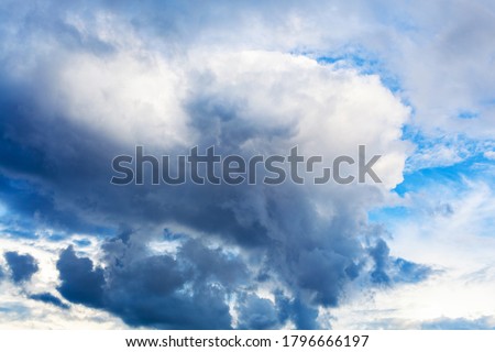 large dark rainy cloud in cloudy blue sky on summer day