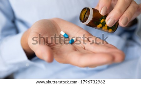 Close up older retired woman taking medicine capsules out of glass bottle. Middle aged elderly grandmother holding vitamins or painkiller antidepressant antibiotic pills in hands, healthcare concept. Royalty-Free Stock Photo #1796732962