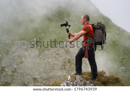 Professional videographer shooting with a gimbal high in the mountains