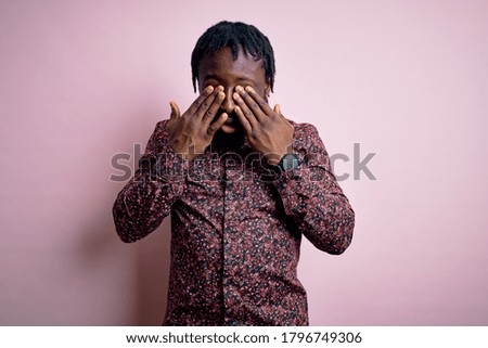 Young handsome african american man wearing casual shirt standing over pink background rubbing eyes for fatigue and headache, sleepy and tired expression. Vision problem