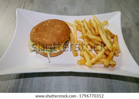 Picture of a small cheeseburger and french fries on a plate.