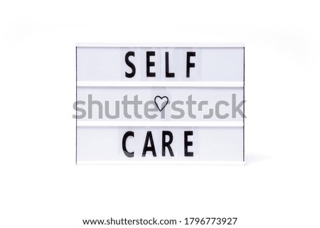 Self care. Text on a vintage lightbox display placed on a white table on a light background.                       