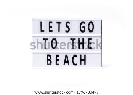 Lets go to the beach. Text on a vintage lightbox display placed on a white table on a light background.                       