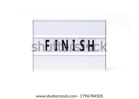 Finish. Text on a vintage lightbox display placed on a white table on a light background.                       