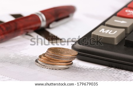 Business still-life of a pen, coin, credit card, charts, calculator
