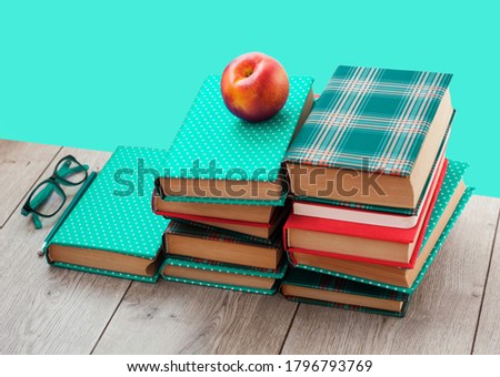 Back to school, pile of books in colorful covers and peach on wooden table with green mint background. Distance home education.Quarantine concept of stay home.