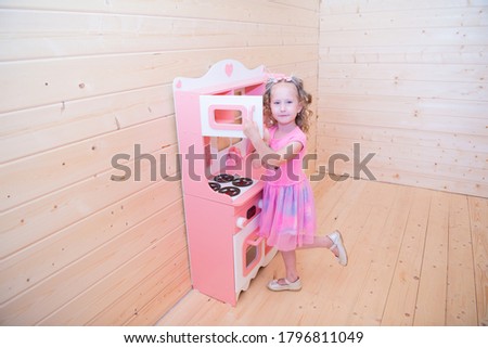 beautiful girl playing in the pink children's kitchen