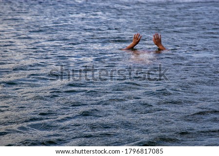 Man hand drowning in the ocean in a sunny day
.The person is drowning in the wavy sea

