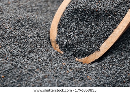 Poppy seeds and wooden scoop, closeup view