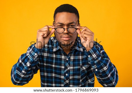 Poor Eyesight. Man In Eyeglasses Looking At Camera Squinting Eyes Having Bad Sight Over Yellow Studio Background. Royalty-Free Stock Photo #1796869093