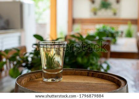 glass with cachaça in wooden barrel. Blurred background. cachaça day is september 13. Brazilian export product, distilled drink known as "aguardente" or "pinga". cachaca. Royalty-Free Stock Photo #1796879884