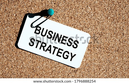 Wooden picture frame with inscription 'business strategy' on beautiful background from dollar bills and metalic pen. Business concept.
