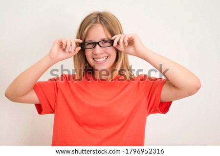 Portrait of happy playful teenager girl in eyeglasses and orange t-shirt.