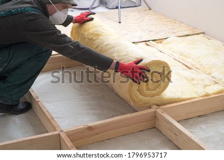 worker insulates the floor with mineral wool Royalty-Free Stock Photo #1796953717