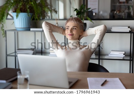 Distracted from job happy peaceful blonde businesswoman relaxing with folded hands behind head, dreaming of future challenges or planning weekend, satisfied with good job done, end of workday. Royalty-Free Stock Photo #1796961943