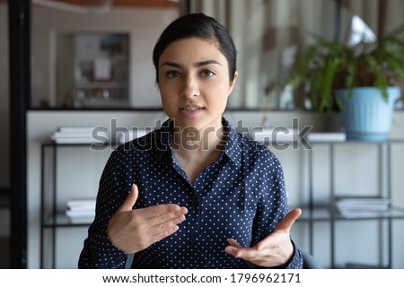Head shot web camera view focused young indian employee holding negotiations video call with clients, discussing project online. Concentrated millennial mixed race job seeker involved in interview. Royalty-Free Stock Photo #1796962171