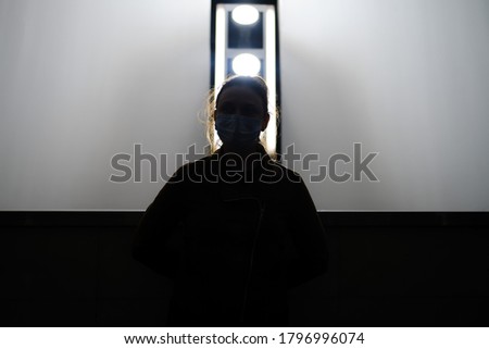 Silhouette of a nurse woman in a face mask on the background of a lamp