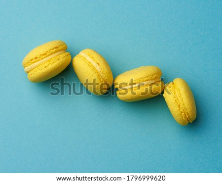 yellow lemon round baked macarons cakes on a blue background, dessert stands in a row, close up, copy space