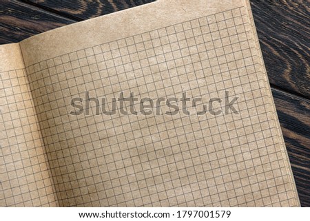Grid paper of notebook background, open sketchbook with blank pages. Top view of vintage graph sheet on wooden desk, texture squared paper of school notepad or diary, retro yellow lined notebook.