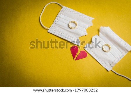 Great concept of divorce in quarantine due to the 2019 coronavirus pandemic. Face mask cut in half with wedding rings. Royalty-Free Stock Photo #1797003232