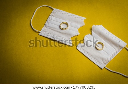 Great concept of divorce in quarantine due to the 2019 coronavirus pandemic. Face mask cut in half with wedding rings. Royalty-Free Stock Photo #1797003235
