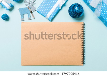 Top view of notebook on blue background made of Christmas decorations. New Year time concept.