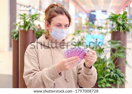 Woman in medical mask with money in hand on street