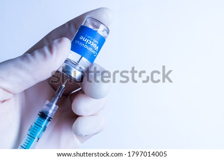 Oxford vaccine - Coronavirus Vaccine - Doctor with surgical glove holding a vaccine vial with the blue label written Coronavirus Vaccine - Sars-Cov-2 over white background Royalty-Free Stock Photo #1797014005