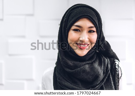 Portrait of happy arabic muslim woman with hijab dress smiling and look at camera on white wall background