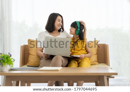 Asian young mother with computer notebook teaching kid to learn or study online at home, Homeschooling online concept Royalty-Free Stock Photo #1797044695