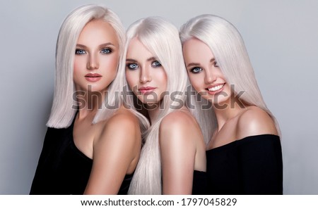 Three beautiful girls with hair coloring in ultra blond. Stylish hairstyle curls done in a beauty salon. Fashion, cosmetics and makeup Royalty-Free Stock Photo #1797045829