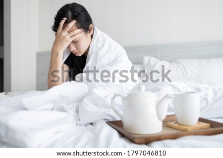Sick asian child girl is holding temple with her hand while sitting in bed feeling tired,uncomfortable,drowsy,dizzy after waking up in the morning,woman have a headache,aching pain touching her head Royalty-Free Stock Photo #1797046810