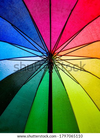 Raindrops seen from the inside of a rainbow coloured umbrella Royalty-Free Stock Photo #1797065110