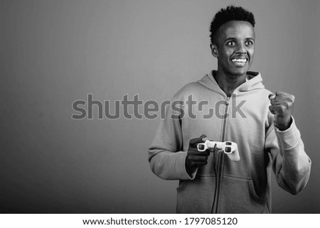 Young handsome African man playing games against gray background