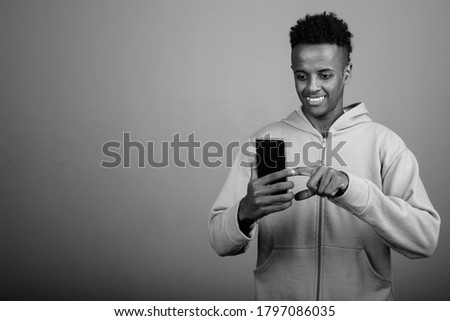 Young handsome African man using phone against gray background