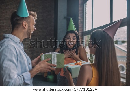 Nice moment. A surprised woman getting birthday gifts from her friends