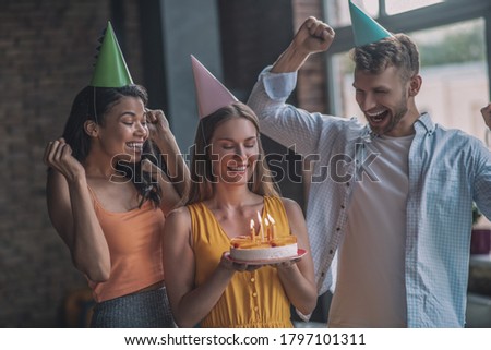 Happy birthday. A woman holding a cake with candles at her birthday party