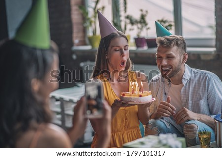 Birthday cake. A woman taking pictures of her friend blowing out candles on the cake