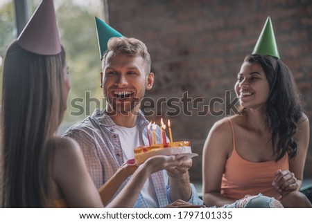 A smiling man blowing out candles on his birthday cake