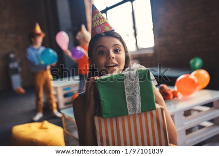 Excitement. Cute girl in a hat holding presents and feeling excited