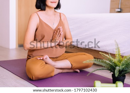 Asian woman sitting practicing doing yoga meditation in bedroom,Workout exercise after waking up in morning,Healthy and lifestyle concept