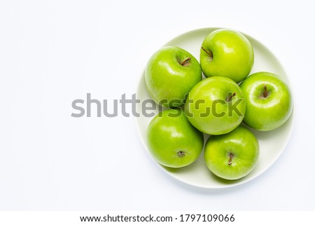 Fresh green apples on  white plate on white background. Copy space