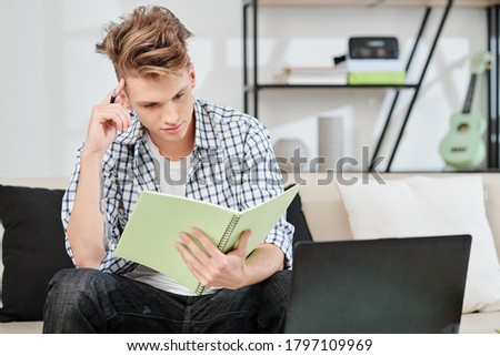 Pensive teenage boy reading information in textbook and trying to memorize things for exam Royalty-Free Stock Photo #1797109969