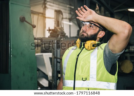 Portrait of professional technician engineer control machine in factory. 
He is a young businessman and owns a large turning mill. The concept of working hard and tired