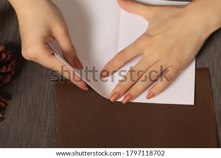 Female hands make paper figures on a cozy brown background with lights and a warm lamp. Hobby and hobby concept