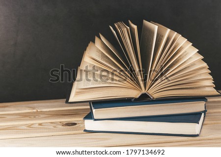 Old books on wooden shelf. Open book with hardback, fanned pages. Home library. Horror story. Vintage literature. Back to school. Education background. Copy space for text.