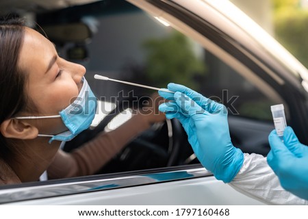 Portrait of asian woman drive thru coronavirus covid-19 test by medical staff with PPE suit by nose swab. New normal healthcare drive thru service and medical concept. Royalty-Free Stock Photo #1797160468