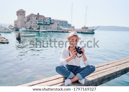 Tourism concept. Young traveling woman enjoying the view of Kastel Gomilica Castle sitting near the sea on Croatian coast.