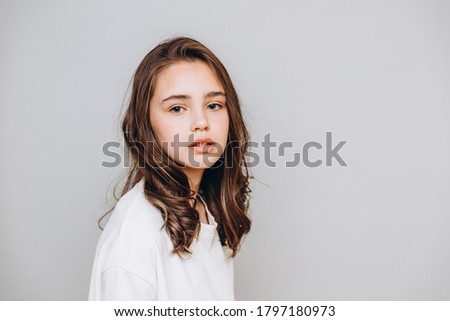 little pretty girl with expressive facial features posing for a photo on a gray background