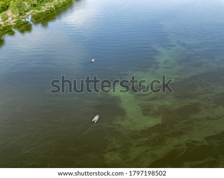 Aerial drone view. Fishing boat on the water. Algae bloom in the water, clouds are reflected.
